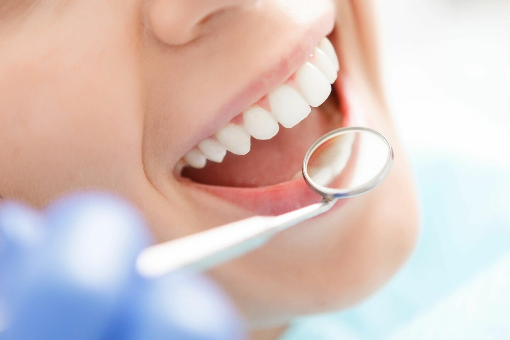 A dentist holding a dental mirror to a person’s mouth