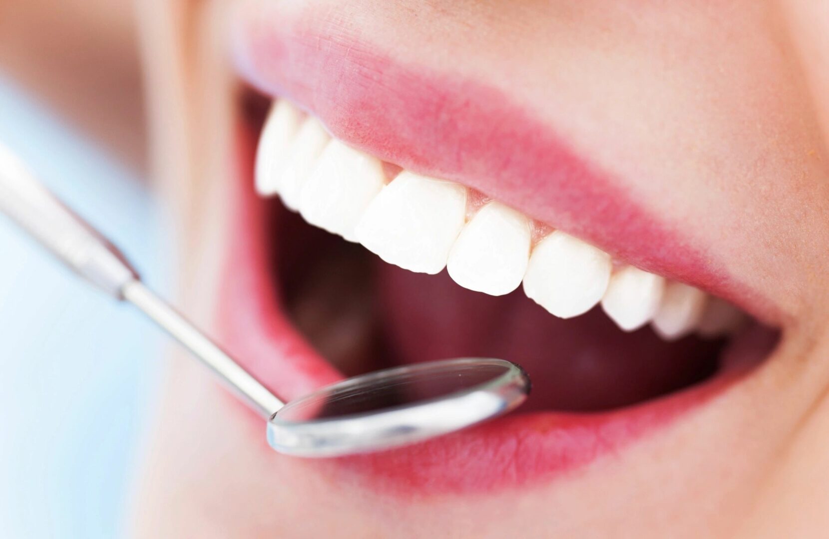 A dental mirror being held at a mouth